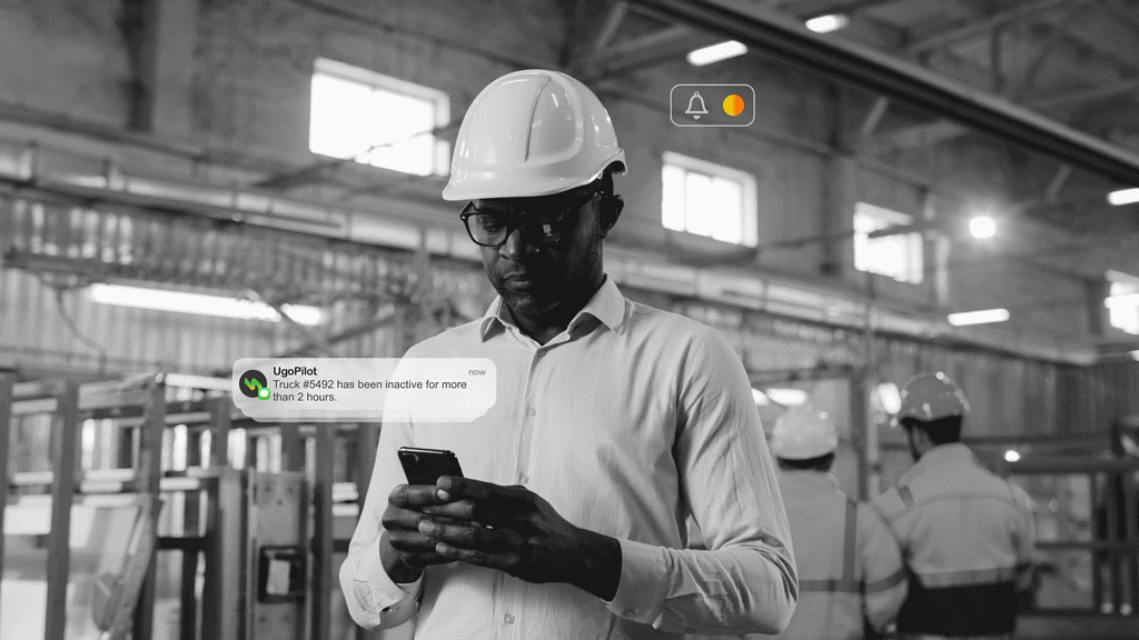 Man looking at a notification from UgoPilot on a cell phone in an industrial context