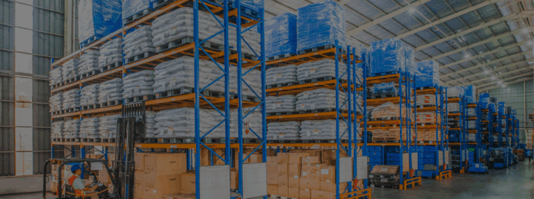 Forklift operating in a warehouse filled with pallets, bags, and stacked boxes.