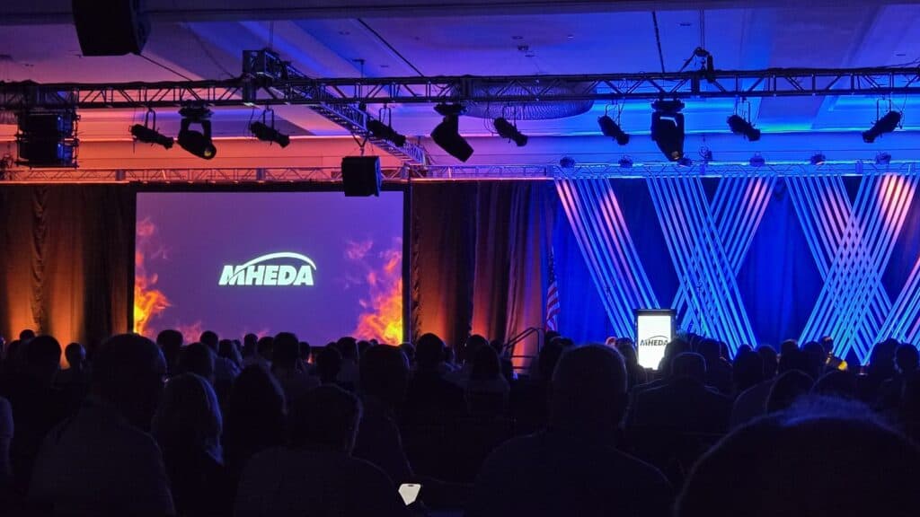 MHEDA conference opening with stage lighting and full audience.