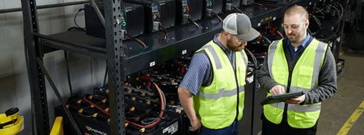Two men in front a battery room