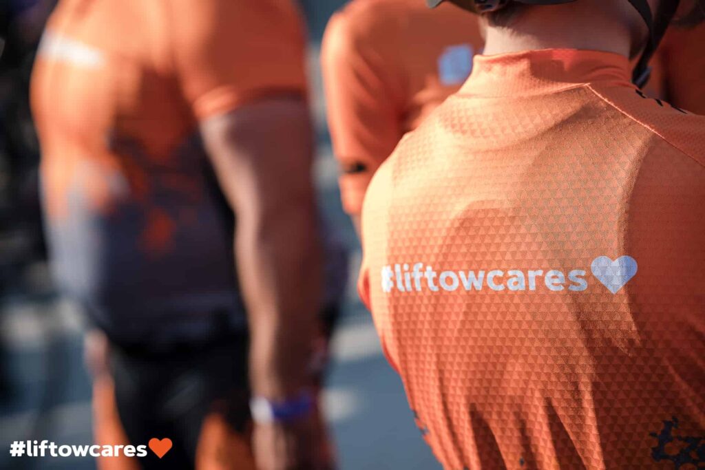 Close up picture of an orange and grey bicycle jersey with #liftowcares on the back.