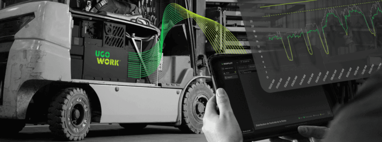 Opérateur manœuvrant un chariot élévateur équipé d'une batterie UgoWork, tandis qu'une autre personne surveille les données énergétiques sur une tablette avec le logiciel UgoPilot.
