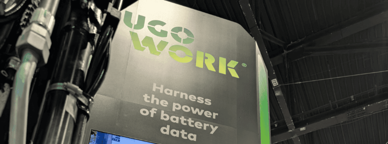 Kiosque de UgoWork lors d’un salon, avec le slogan "Harness the power of battery data" sous le logo vert de UgoWork.