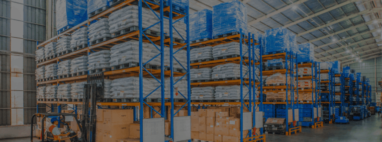 Forklift operating in a warehouse filled with pallets, bags, and stacked boxes.