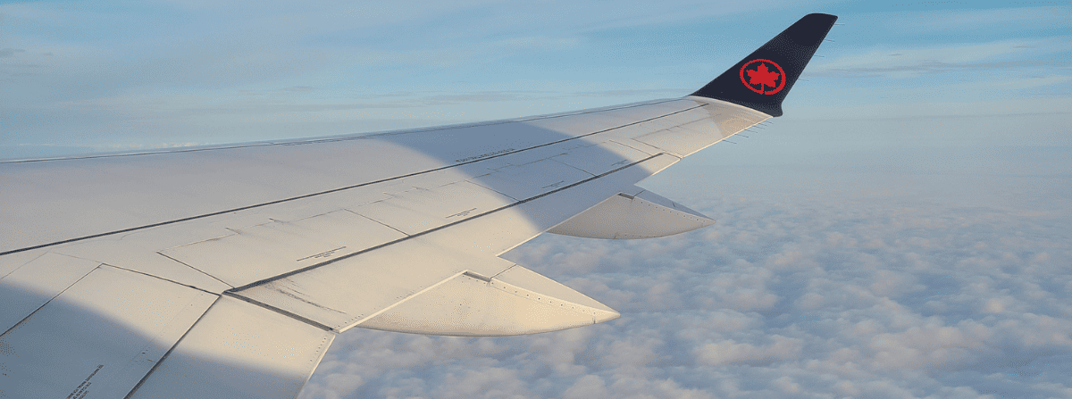 View of Air Canada wing above the clouds during flight.