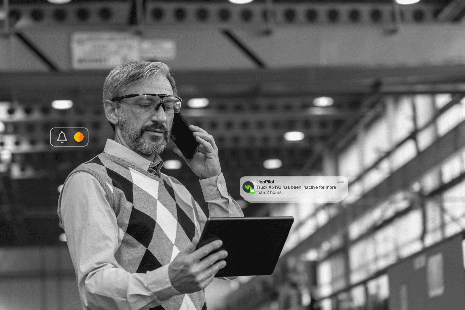 Employee using UgoWork platform with tablet and phone in industrial setting, managing vehicle activity.