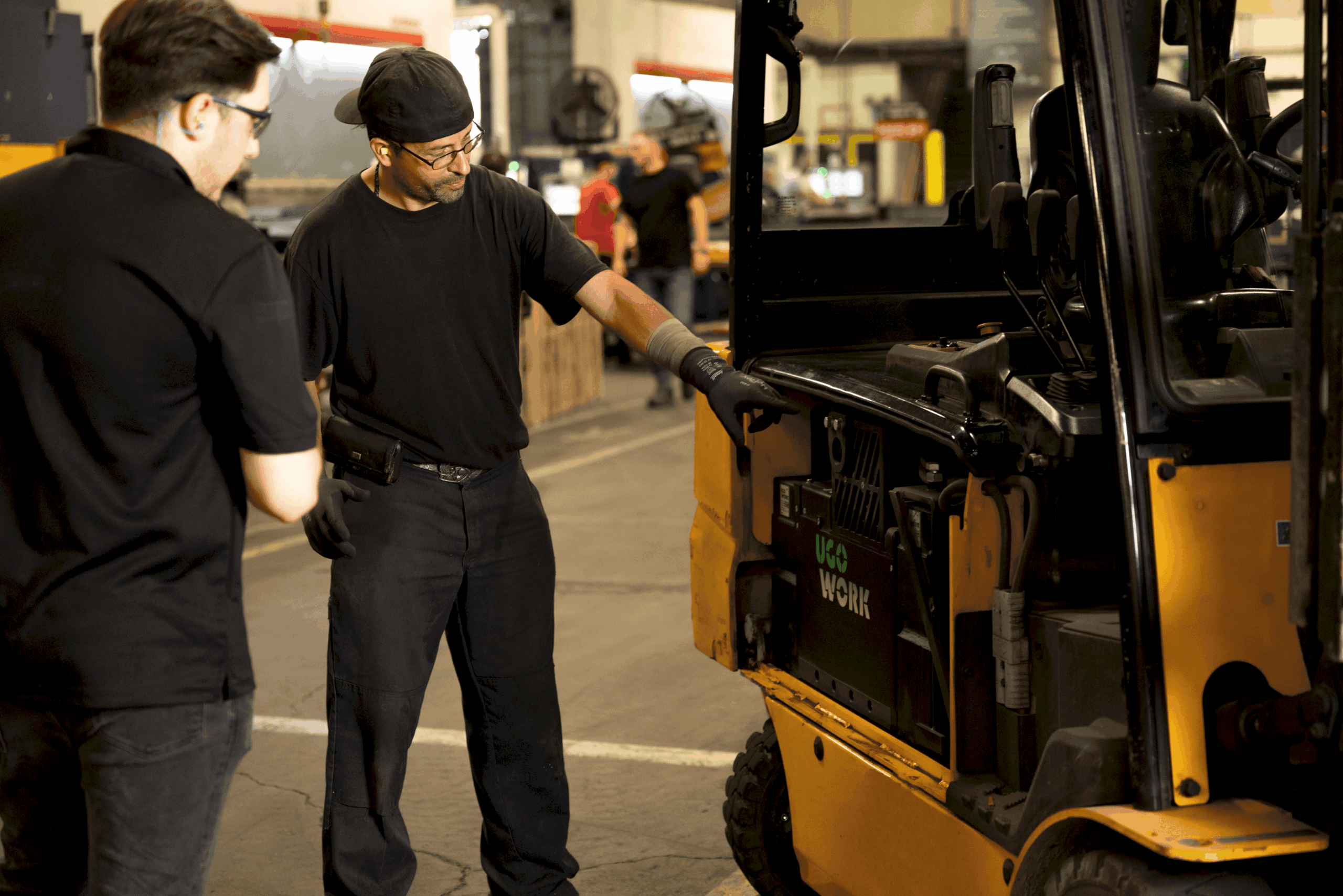 Un expert en énergie et un technicien discutent à côté d'un chariot élévateur équipé d'une batterie lithium-ion UgoWork.
