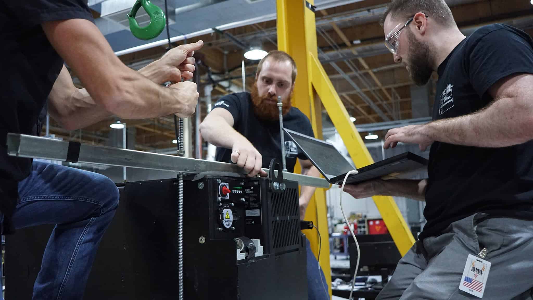 Industrial mechanical and electrical engineers working on a UgoWork lithium-ion battery at a HALT testing facility as part of their R&D process.