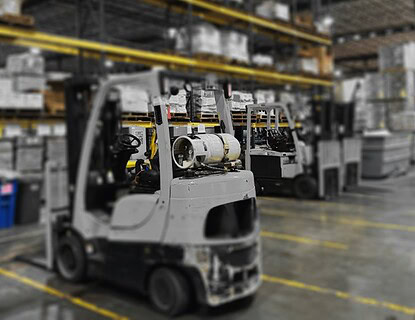 Propane powered forklift in warehouse with storage shelves and boxes, industrial logistics equipment.