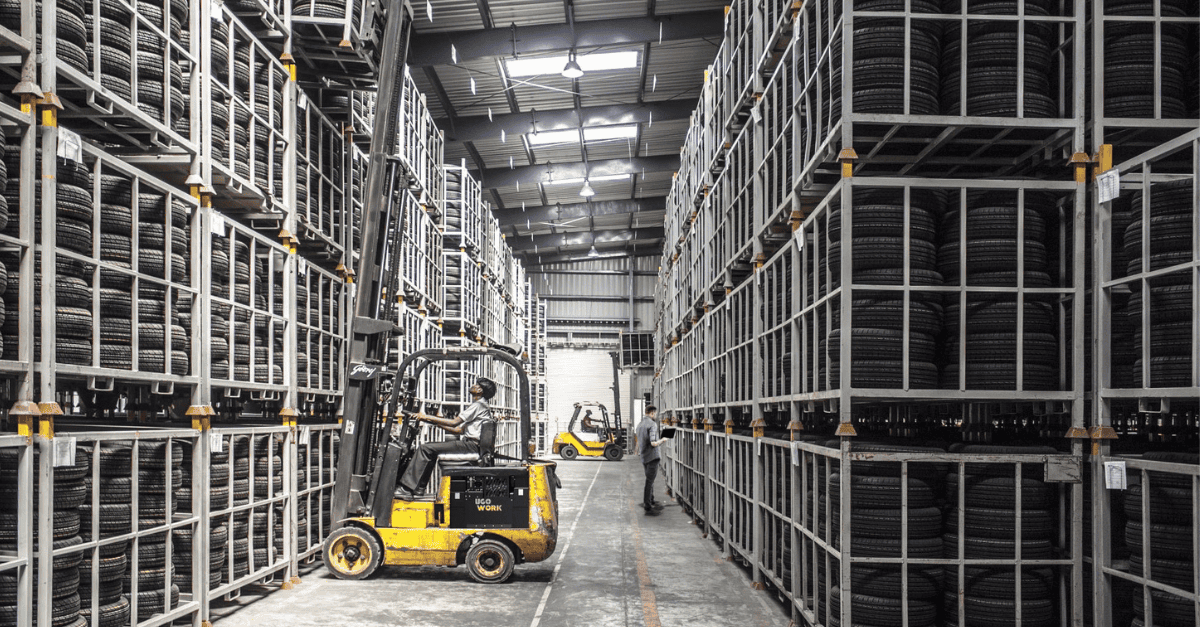 Forklift navigating tire storage warehouse aisle with UgoWork battery system